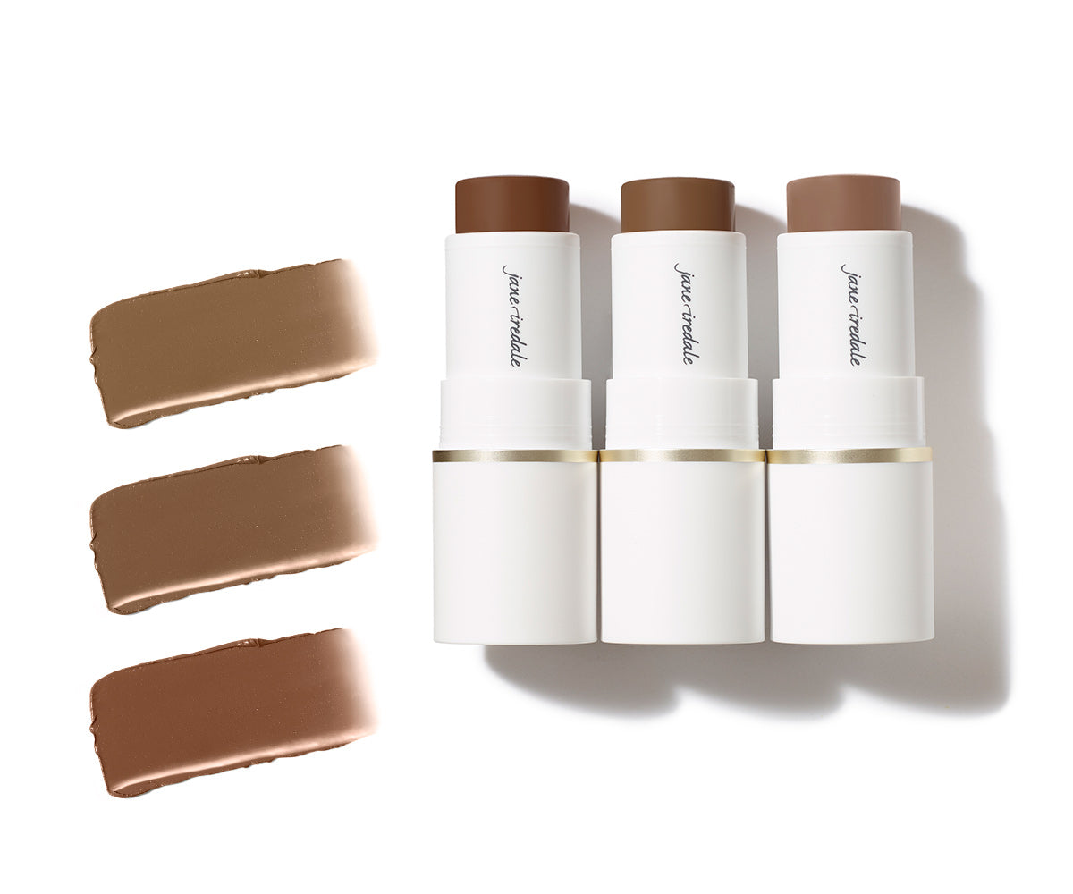 Drei nebeneinander liegende Jane Iredale Bronzer-Sticks in weißen Gehäusen mit verschiedenen Brauntönen; links daneben drei cremige Texturproben in entsprechenden Nuancen auf weißem Hintergrund.