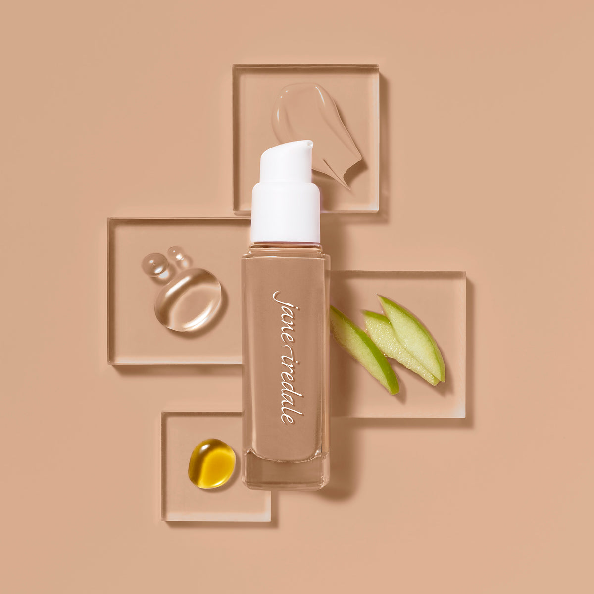Die jane iredale Flüssigfoundation Skintuition in einer Glasflasche mit Pumpspender, umgeben von Abbildungen enthaltener Inhaltsstoffe